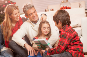 Children opening Christmas presents at home with their parents