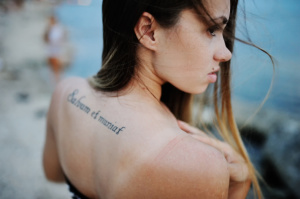 girl with a tattoo on his back against the sea